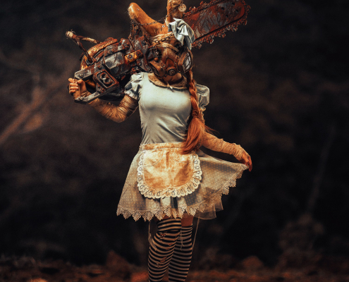 Frau im Alice Kleid mit Hasenmaske und großer Kettensäge, verstörend